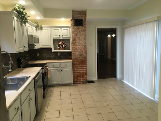 kitchen with light countertops, white cabinets, tasteful backsplash, light tile patterned floors, and stainless steel appliances