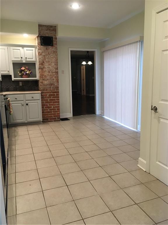 kitchen featuring light tile patterned floors, baseboards, tasteful backsplash, and white cabinetry
