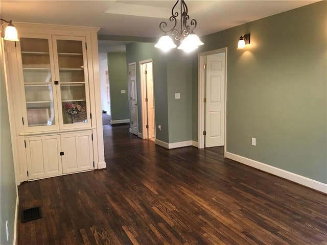 unfurnished dining area featuring baseboards, dark wood finished floors, and visible vents