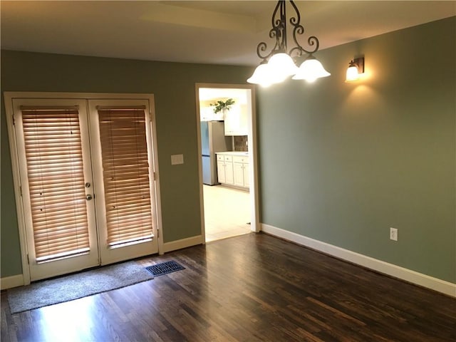 unfurnished dining area with a notable chandelier, baseboards, visible vents, and dark wood-style floors