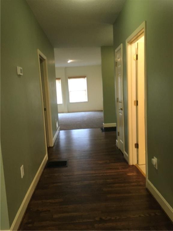 hallway featuring baseboards and dark wood-style flooring