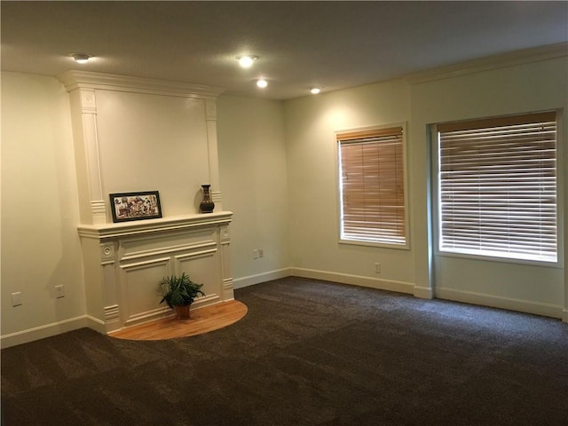 unfurnished living room with baseboards and dark colored carpet
