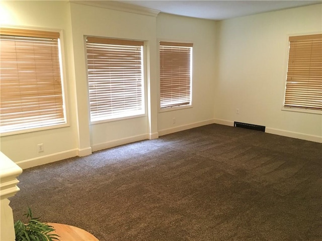 unfurnished room with baseboards, visible vents, and dark colored carpet