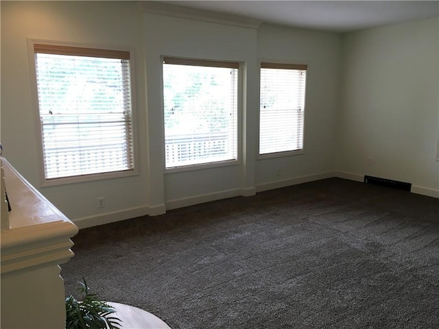 empty room featuring baseboards and dark colored carpet