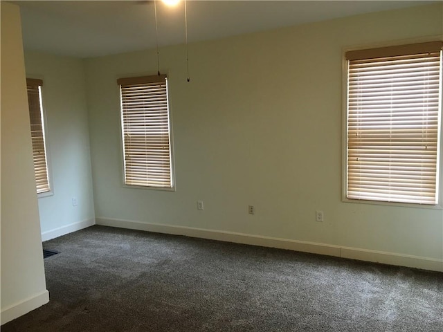 empty room featuring baseboards and dark carpet