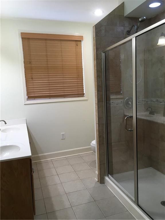 full bathroom with double vanity, tile patterned flooring, a stall shower, baseboards, and toilet