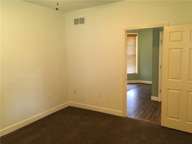empty room with visible vents, baseboards, and dark colored carpet