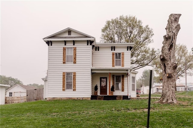 italianate home with fence, covered porch, and a front yard