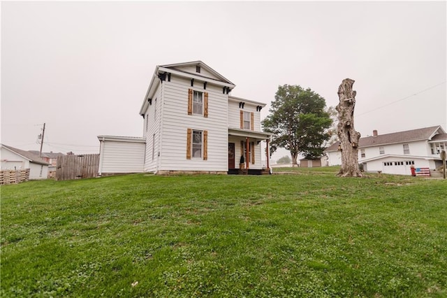 back of house featuring a lawn, fence, and covered porch