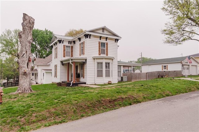 view of front of home with central air condition unit, fence, and a front lawn