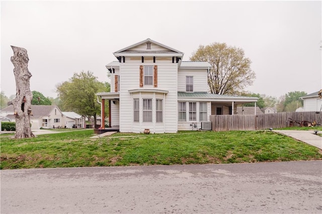 view of front of property with central AC unit, a front lawn, fence, and metal roof