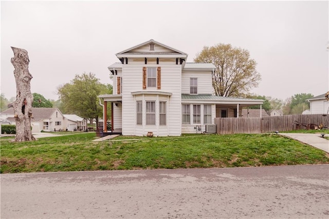 view of front of house with central AC unit, fence, and a front yard