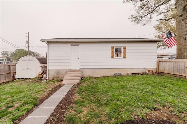 rear view of house with a fenced backyard, a yard, entry steps, and a shed