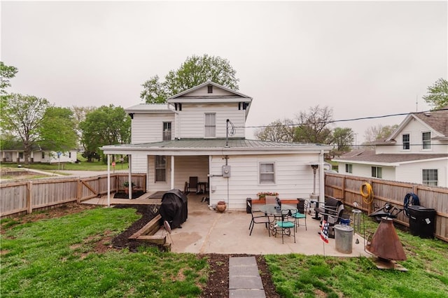 back of property with a fenced backyard, a standing seam roof, a patio area, metal roof, and a yard