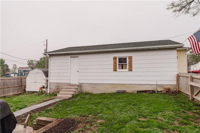 rear view of house featuring a lawn, a storage shed, and a fenced backyard