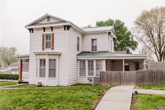 view of front facade featuring fence, cooling unit, metal roof, and a front yard