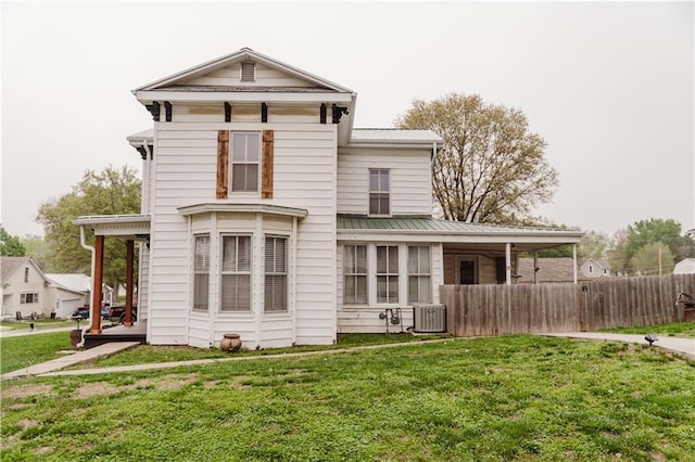 back of property with a lawn, fence, metal roof, and central air condition unit
