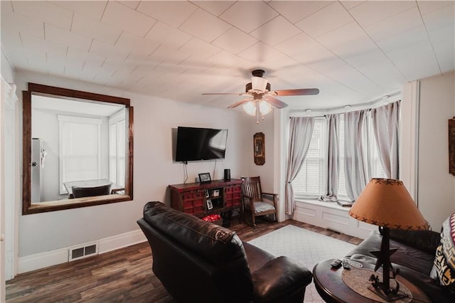living area with visible vents, dark wood finished floors, ceiling fan, and baseboards