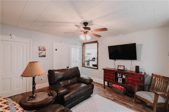 living room featuring a ceiling fan, baseboards, and wood finished floors