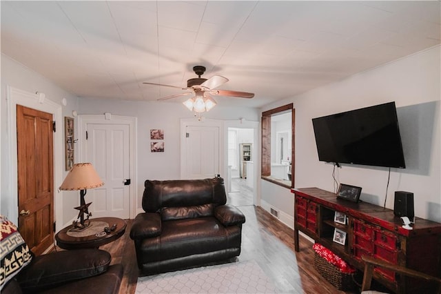 living room featuring baseboards, ceiling fan, visible vents, and wood finished floors