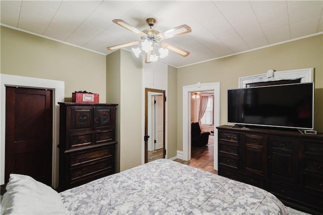 bedroom with crown molding, a ceiling fan, baseboards, and wood finished floors