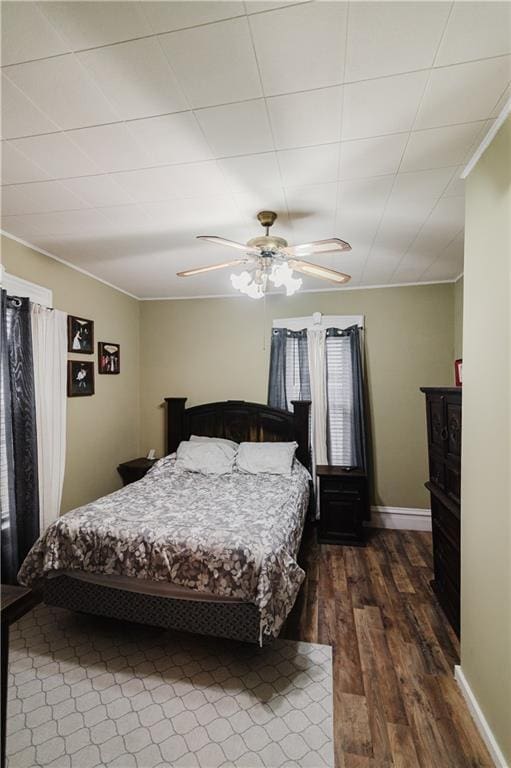 bedroom featuring crown molding, ceiling fan, baseboards, and dark wood-type flooring