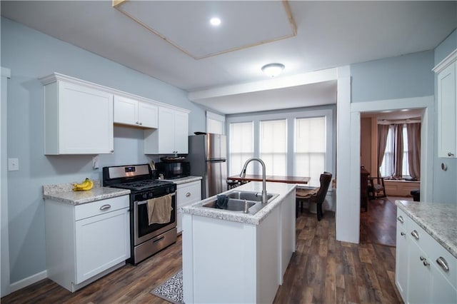 kitchen with dark wood-style flooring, a kitchen island with sink, light countertops, a sink, and stainless steel appliances