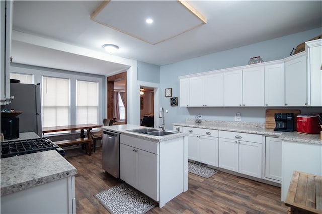 kitchen with stainless steel dishwasher, freestanding refrigerator, an island with sink, white cabinetry, and a sink