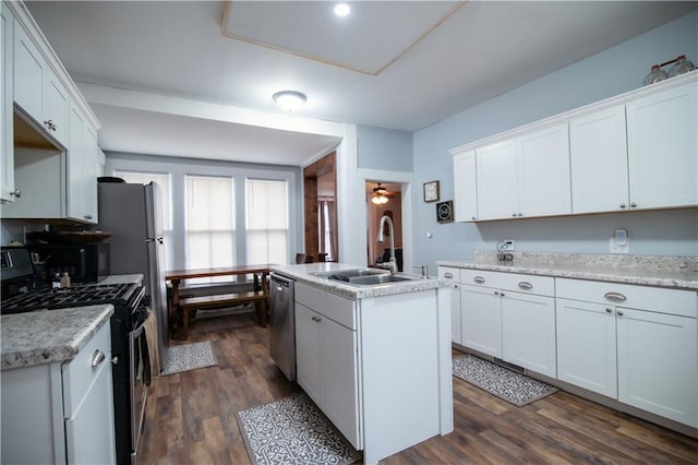 kitchen featuring a sink, light countertops, white cabinets, stainless steel appliances, and an island with sink