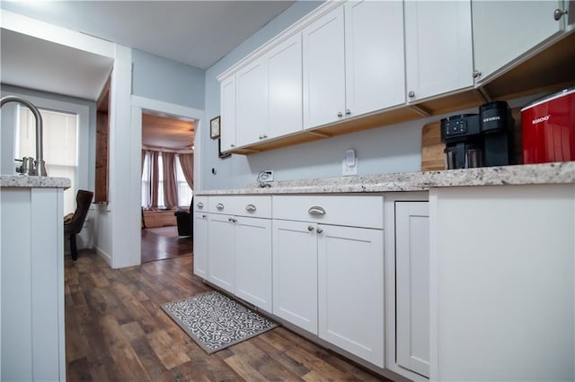 kitchen featuring light stone counters, white cabinets, and dark wood-style floors
