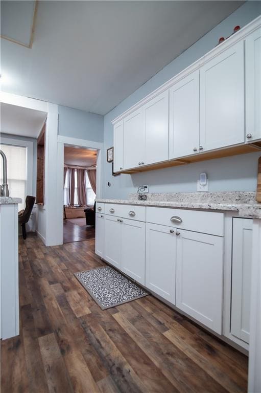 kitchen with white cabinets, light stone counters, and dark wood-style floors