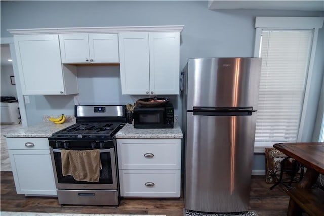 kitchen with stainless steel appliances, light stone countertops, dark wood-style floors, and white cabinetry