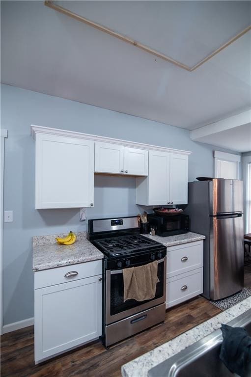kitchen with appliances with stainless steel finishes, white cabinets, and dark wood finished floors