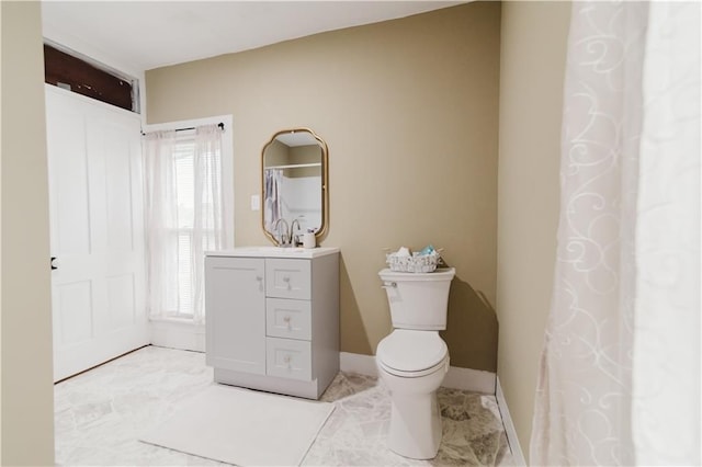 bathroom with vanity, baseboards, plenty of natural light, and toilet