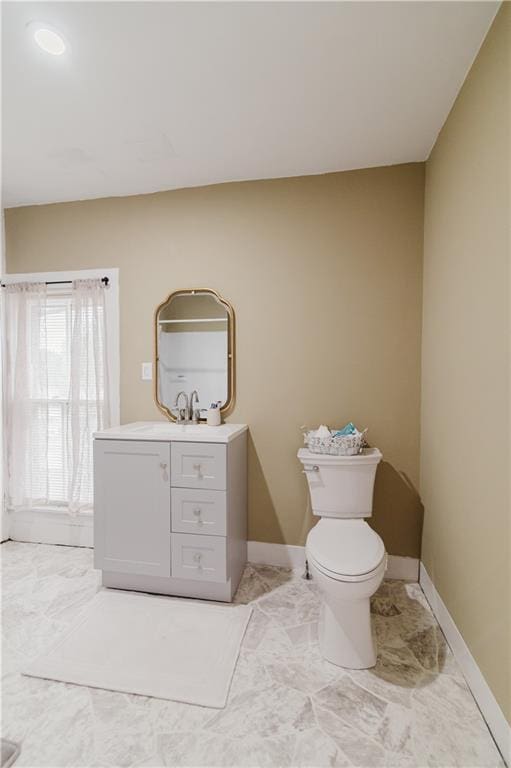 bathroom featuring baseboards, marble finish floor, toilet, and vanity