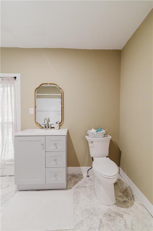 bathroom with toilet, baseboards, marble finish floor, and vanity