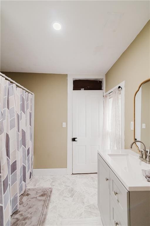 bathroom with vanity, marble finish floor, and baseboards