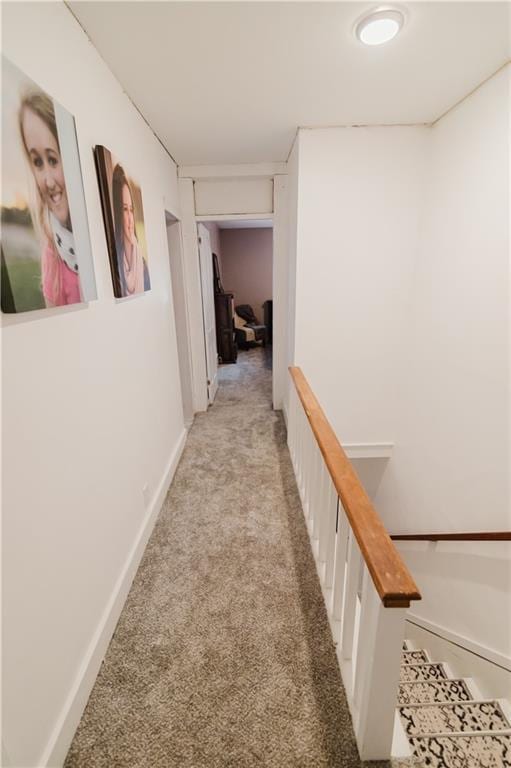 hall featuring baseboards and light carpet