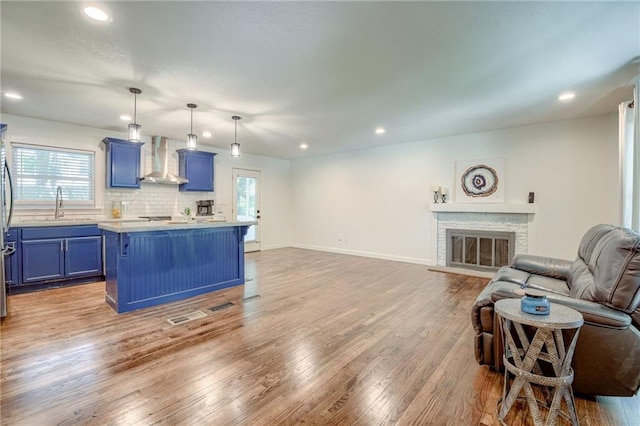 7636 Windsor St, Prairie Village, KS 66208 - kitchen with blue cabinets, wall chimney exhaust hood, open floor plan, a sink, and light countertops