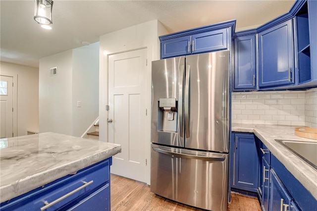 7636 Windsor St, Prairie Village, KS 66208 - kitchen featuring stainless steel fridge with ice dispenser, blue cabinetry, light wood finished floors, and decorative backsplash