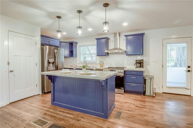 7636 Windsor St, Prairie Village, KS 66208 - kitchen featuring wall chimney exhaust hood, stainless steel appliances, blue cabinets, a breakfast bar area, and decorative backsplash
