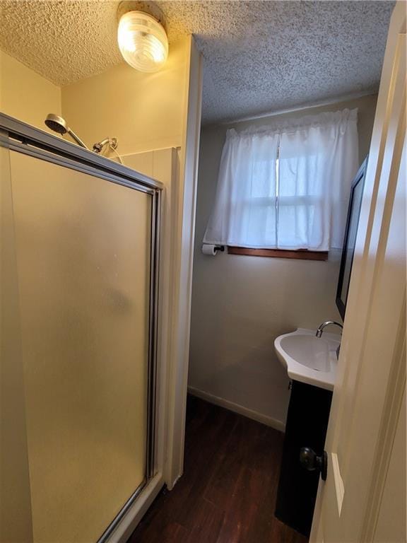 601 S 24th St, Lexington, MO 64067 - bathroom featuring a textured ceiling, wood finished floors, a stall shower, and a sink