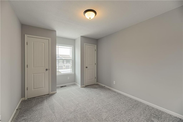 11802 N Bellaire Ave, Kansas City, MO 64156 - unfurnished bedroom with light colored carpet, baseboards, and a textured ceiling