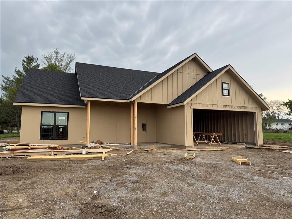 unfinished property featuring roof with shingles and a garage