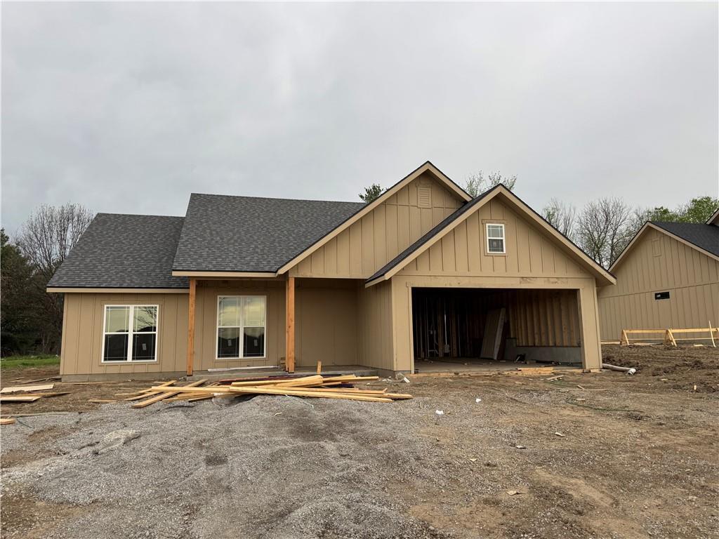property under construction featuring board and batten siding, an attached garage, and roof with shingles