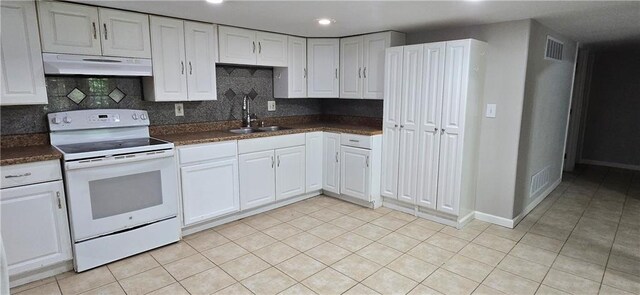 9201 N Harrison St, Kansas City, MO 64155 - kitchen with electric stove, under cabinet range hood, a sink, dark countertops, and light tile patterned floors