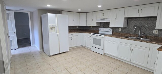 9201 N Harrison St, Kansas City, MO 64155 - kitchen with white appliances, under cabinet range hood, a sink, white cabinets, and light tile patterned floors