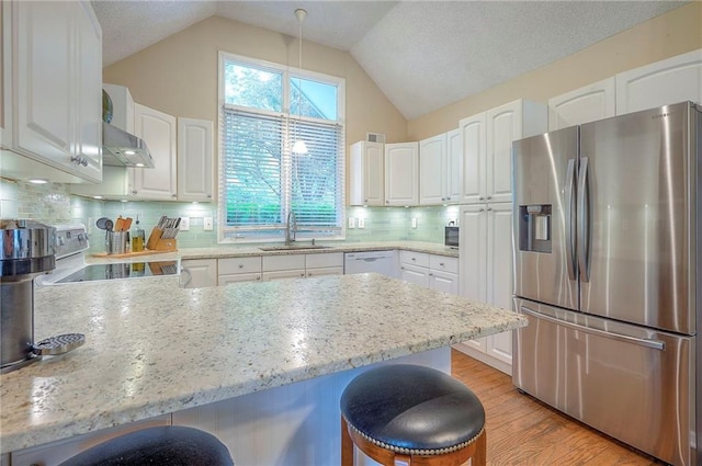 kitchen with stainless steel fridge, a kitchen breakfast bar, a sink, a peninsula, and white cabinetry