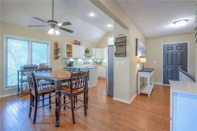 dining space featuring a ceiling fan, baseboards, wood finished floors, vaulted ceiling, and recessed lighting