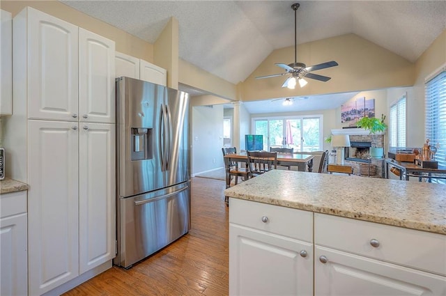 kitchen with stainless steel fridge, a ceiling fan, light wood-style floors, lofted ceiling, and white cabinetry